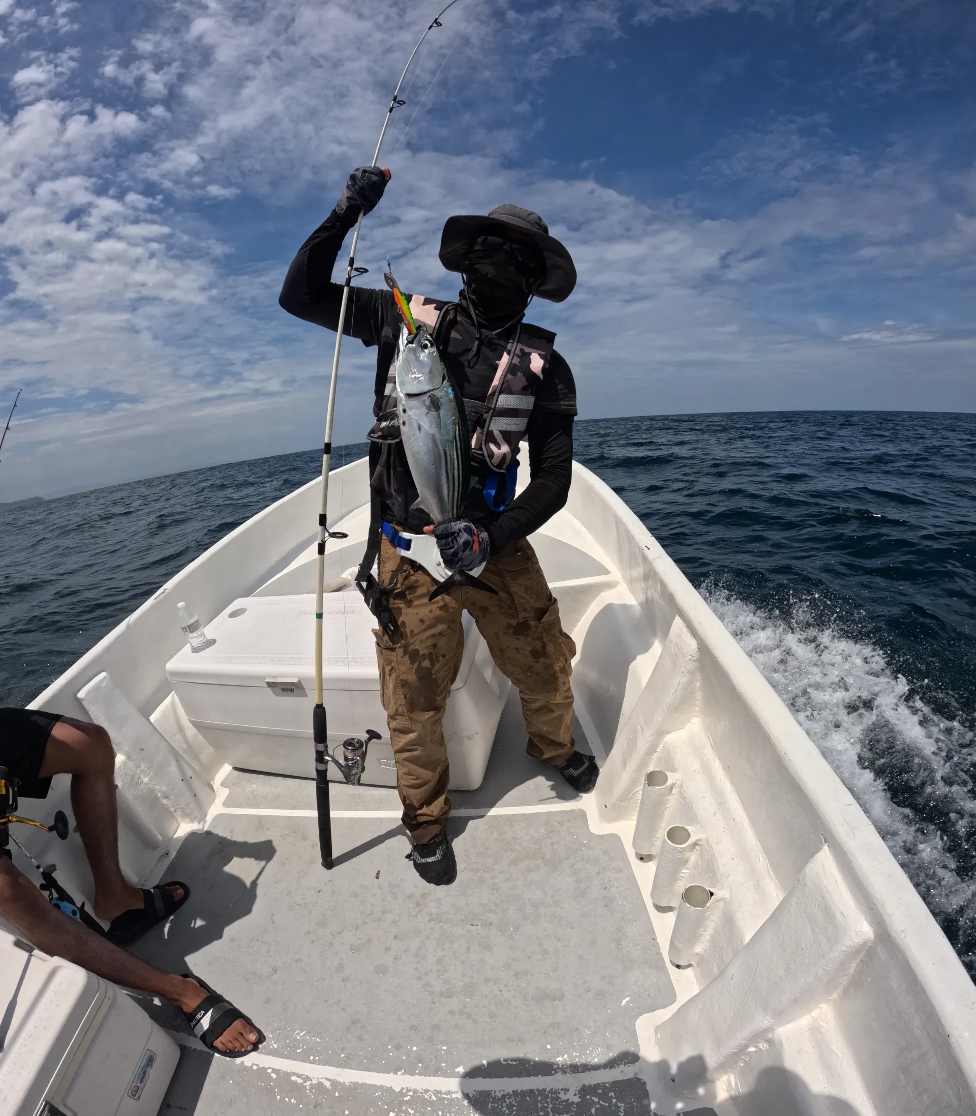 Triunfal Captura de un Vibrante Pez Bonito - En una de las fotos destacadas de nuestra jornada, vemos a Charle en el preciso momento en que saca un pez bonito del agua, capturado a través del emocionante método de pesca trolling. Este fue el preludio de su posterior gran logro, la captura del impresionante pargo roquero. El rostro de concentración de Charle y la majestuosidad del bonito reflejan la pura emoción y la belleza de la pesca en Cambutal.