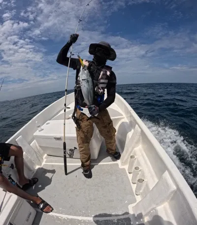 Triunfal Captura de un Vibrante Pez Bonito - En una de las fotos destacadas de nuestra jornada, vemos a Charle en el preciso momento en que saca un pez bonito del agua, capturado a través del emocionante método de pesca trolling. Este fue el preludio de su posterior gran logro, la captura del impresionante pargo roquero. El rostro de concentración de Charle y la majestuosidad del bonito reflejan la pura emoción y la belleza de la pesca en Cambutal.