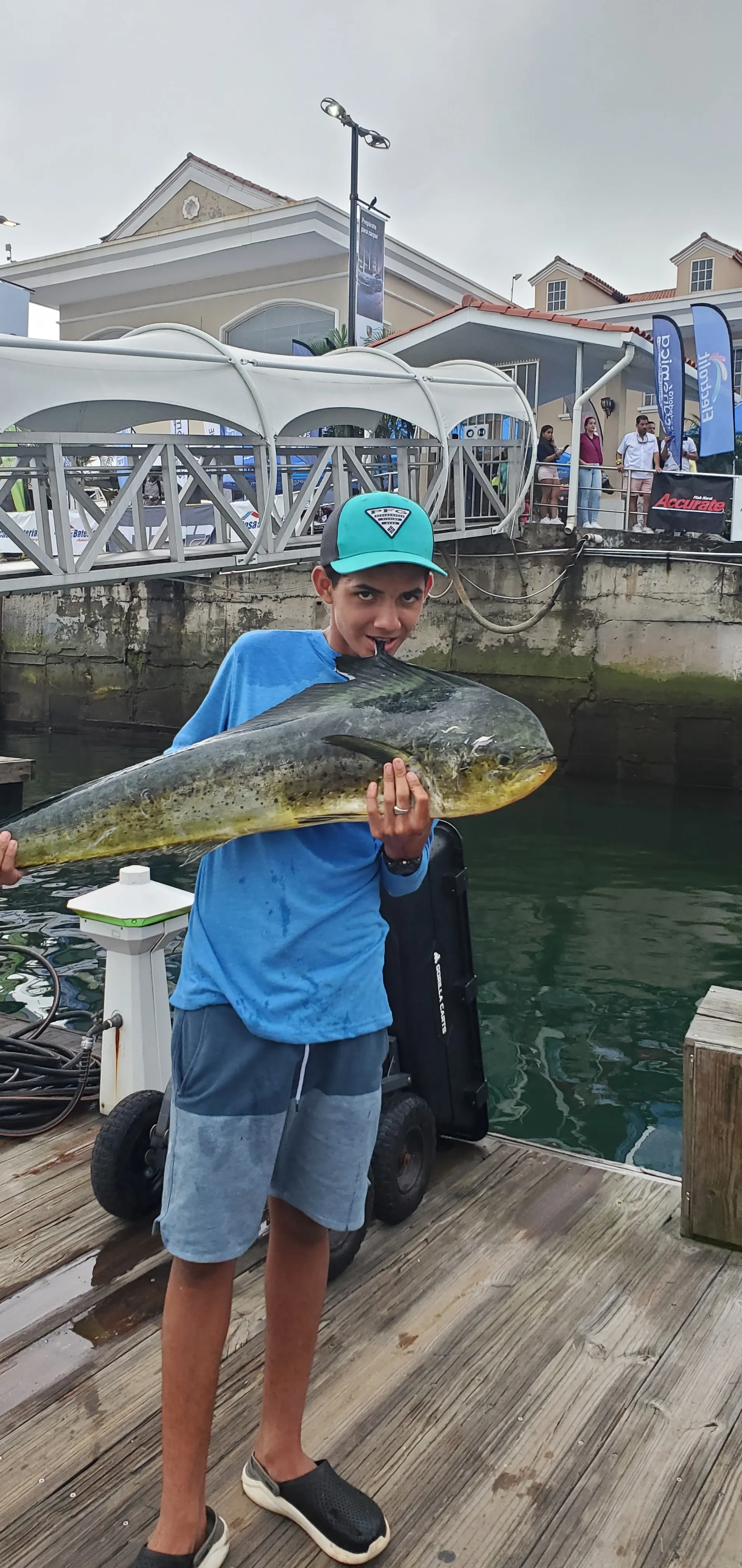 "El legado continúa: El hijo de Igens Cruz sostiene un dorado en el lugar de pesaje del torneo - Esta emotiva fotografía captura un momento de trascendencia en la historia de la pesca familiar. En el lugar de pesaje del torneo, el hijo de Igens Cruz, siguiendo los pasos de su padre, sostiene con orgullo un impresionante pez dorado capturado en las aguas de Panamá. El brillo dorado del pez contrasta con la expresión de determinación y satisfacción en el rostro del joven pescador.

La imagen transmite la continuación de un legado familiar y la pasión por la pesca que se ha transmitido de generación en generación. El dorado en las manos del hijo de Igens Cruz representa la culminación de su esfuerzo y dedicación en este torneo, donde compite con otros apasionados pescadores por el reconocimiento y el premio.