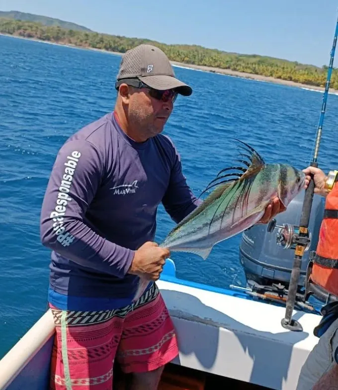 El Gallo de Palo Seco: Una Captura para Recordar - Aquí, el pescador muestra un Pez Gallo, una especie muy reconocida y apreciada por los pescadores en Palo Seco. Esta impresionante captura habla del potencial que ofrece este destino para la pesca deportiva.